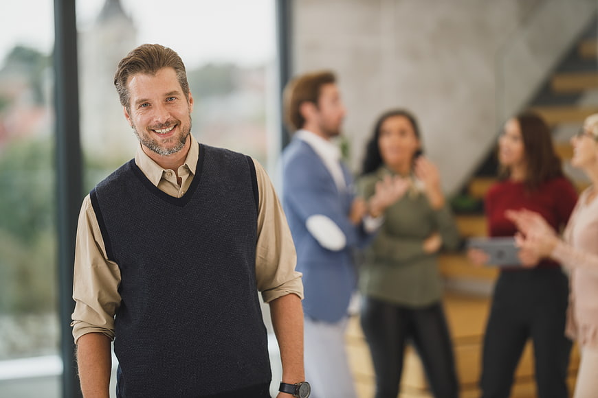 Smiling Businessman in Office with Colleagues