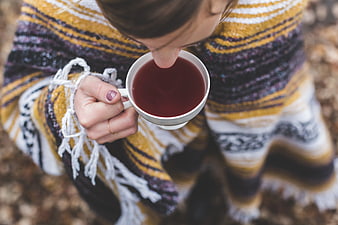 Woman Drinking Hot Tea in Cozy Striped Blanket