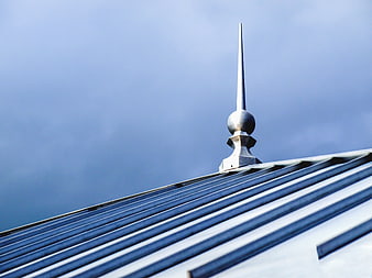 Metal Roof Spire Against Blue Sky