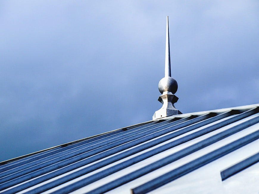 Metal Roof Spire Against Blue Sky