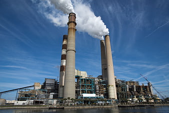 Industrial Power Plant Smoke Stacks Emitting Steam Against Blue Sky