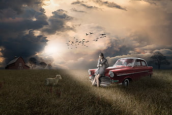 Woman leaning on vintage red car in dramatic field