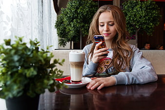 Teenage Girl Using Smartphone at Cafe with Iced Coffee