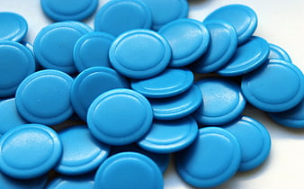 Close-up of blue round plastic game tokens on white background