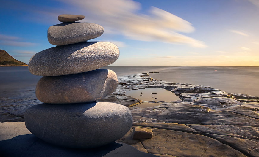 Balanced Stone Stack on Rocky Coastline at Sunset
