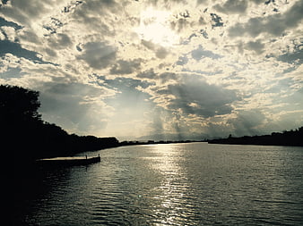 Dramatic sun rays over a river with silhouetted banks