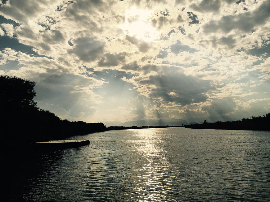 Dramatic sun rays over a river with silhouetted banks