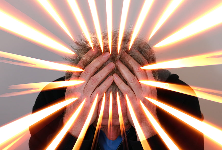 Senior man holding head with glowing light rays representing stress