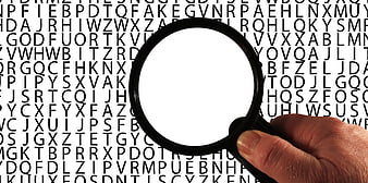 Hand holding magnifying glass over text background