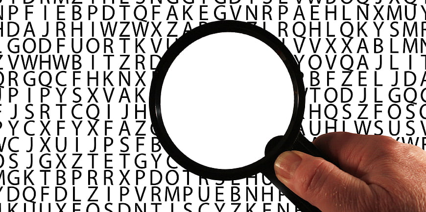 Hand holding magnifying glass over text background