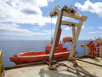 Orange rescue boat on offshore vessel deck with crew