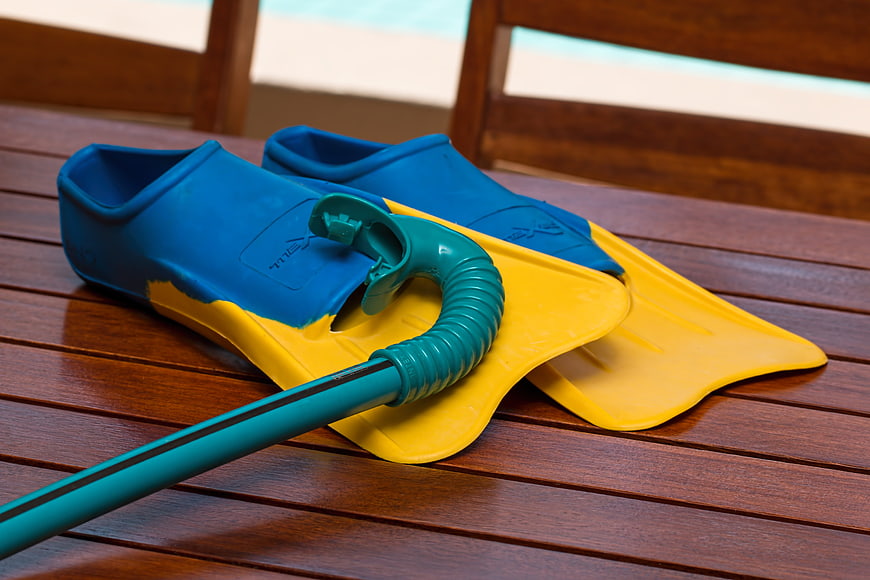 Blue and yellow swim fins with snorkel on wooden deck