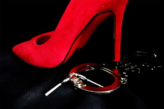 Red suede high heel shoe with handcuffs on black background