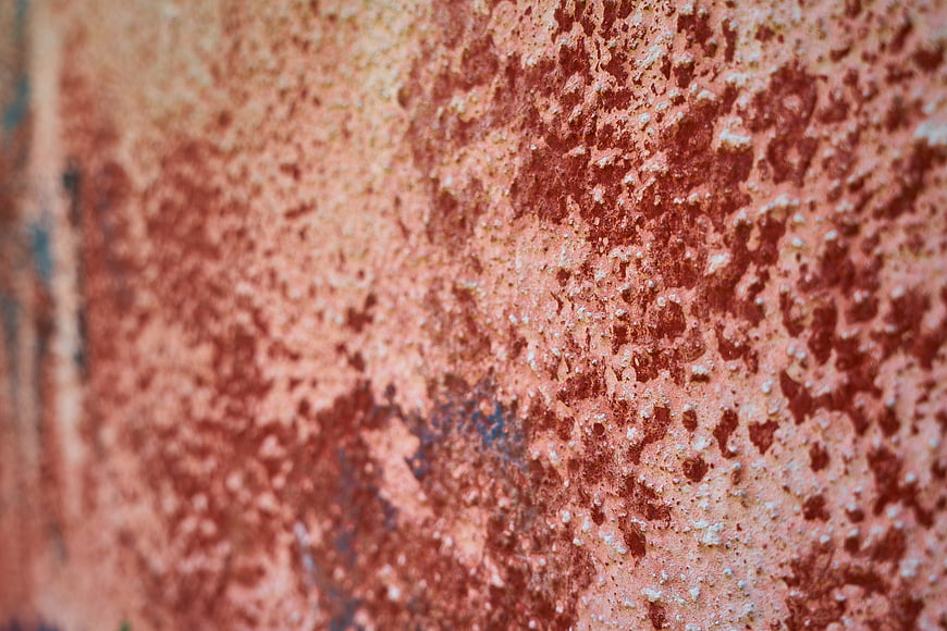 Close-up of textured rusty red stone wall surface