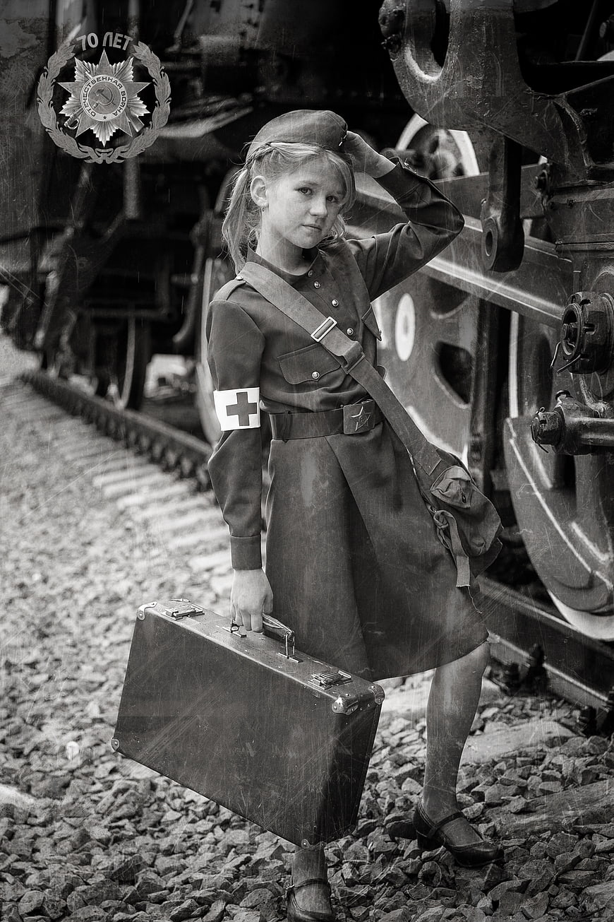 Young Girl in Military Uniform Holding Suitcase Near Train
