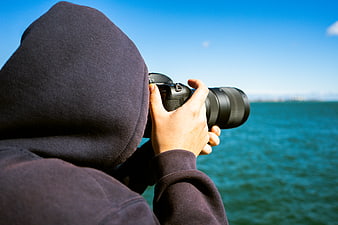 Photographer in Hoodie Taking Photo of Ocean View
