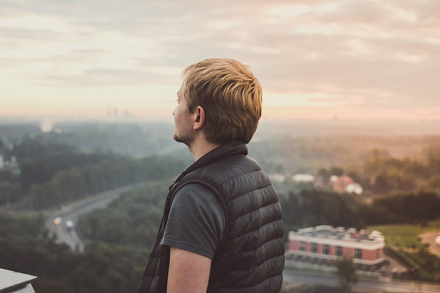 Man Looking at City View from Rooftop at Sunset
