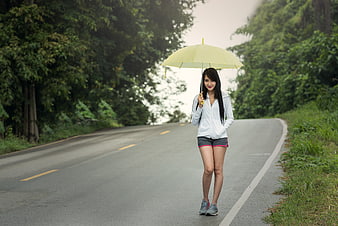 Young Woman Walking on Road with Yellow Umbrella