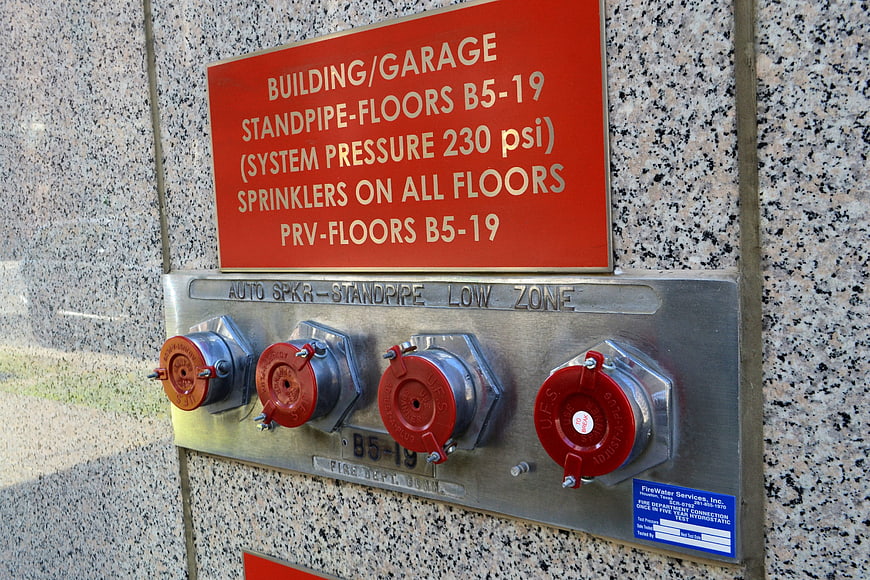 Exterior building standpipe system with red fire safety valves and signage