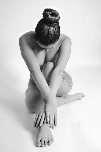 Black and white artistic nude portrait of a woman in a seated pose