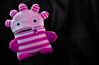 Pink and White Striped Plush Worry Eater Toy on Black Background
