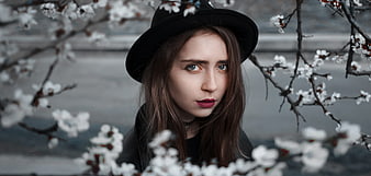 Portrait of young woman in black hat with spring blossoms