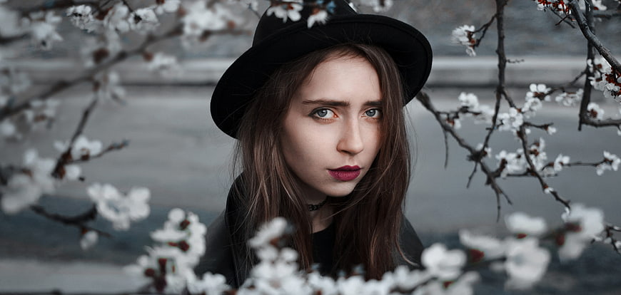 Portrait of young woman in black hat with spring blossoms