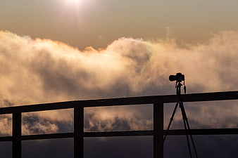 Camera on Tripod Silhouette Against Golden Clouds