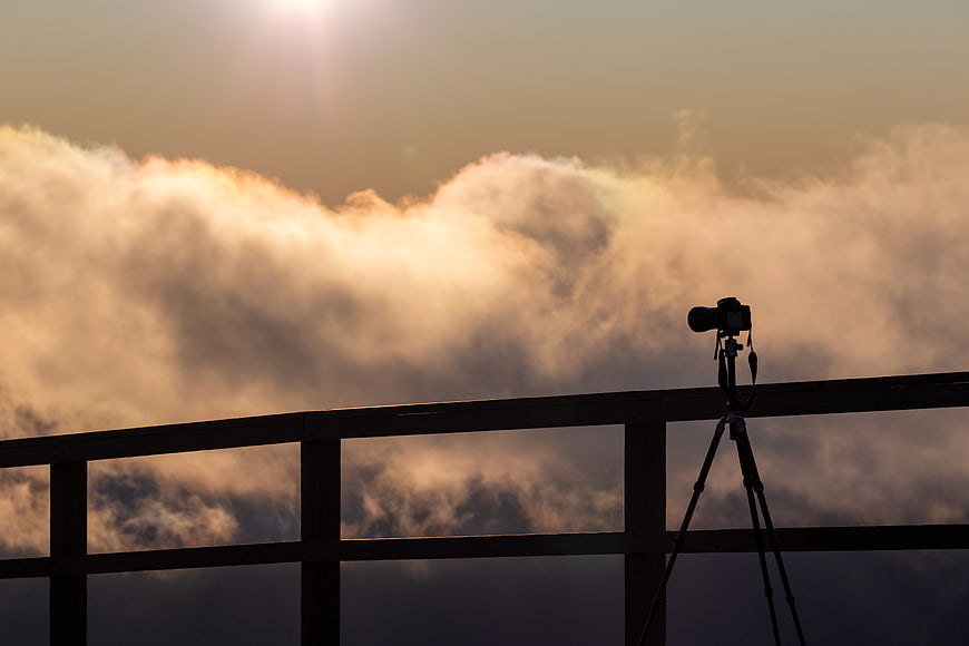 Camera on Tripod Silhouette Against Golden Clouds