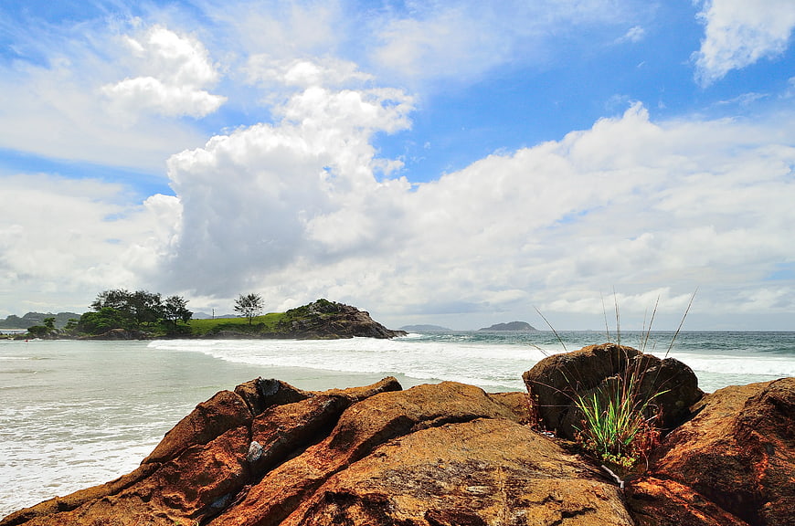 Rugged Coastal Rocks with Green Island and Blue Sky