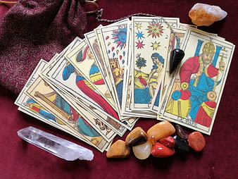 Tarot cards spread with crystals and pendulum on red cloth