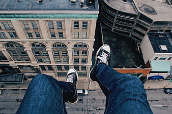 First-person view of legs dangling over city rooftop edge