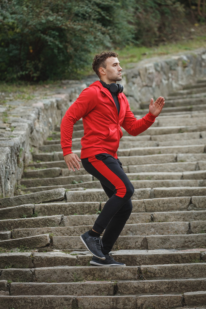 Athletic Man Running Up Stone Stairs in Red Hoodie