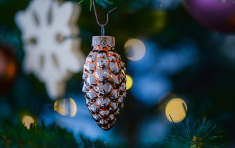 Close-up of a textured pinecone Christmas ornament on a tree