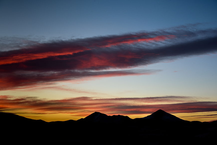 Dramatic sunset silhouette of mountain peaks with red clouds