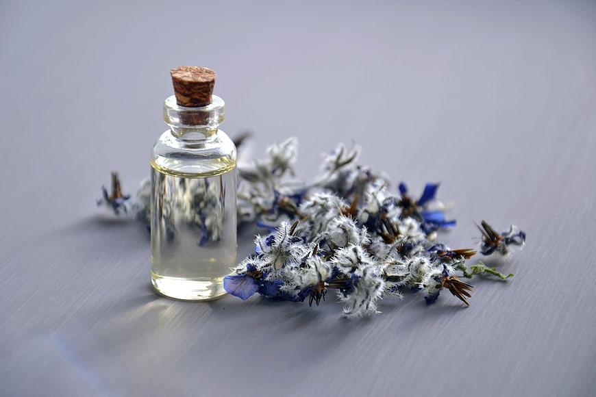 Glass bottle of borage essential oil with dried flowers