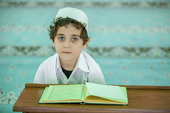 Young Muslim boy reading Quran in mosque