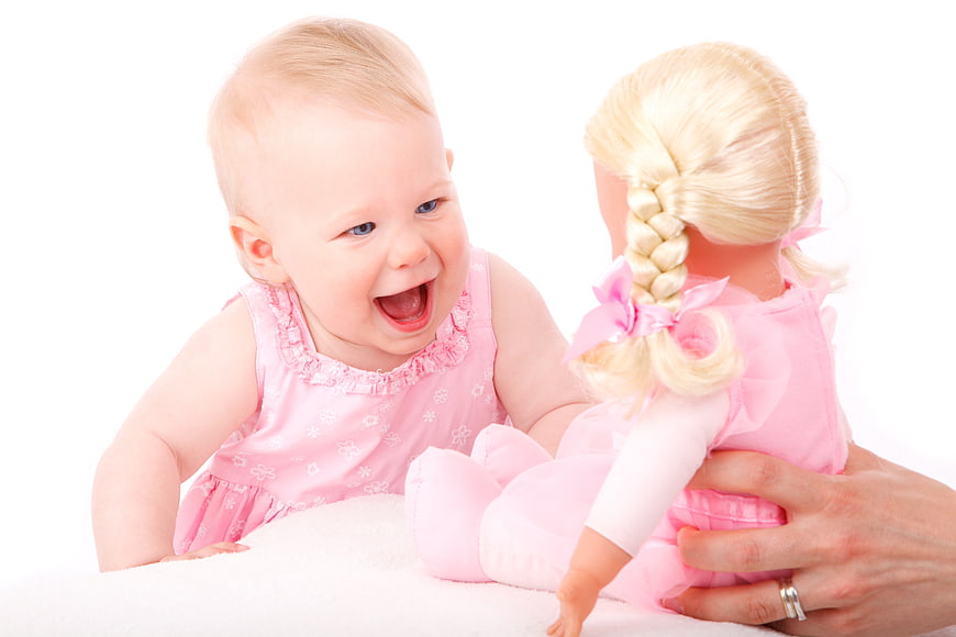 Laughing Baby Girl Playing With Pink Doll On White Background