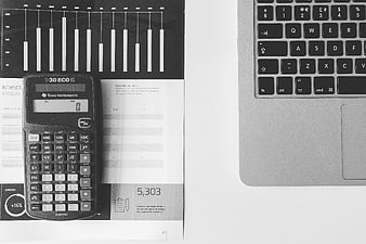 Black and white calculator and laptop on financial report