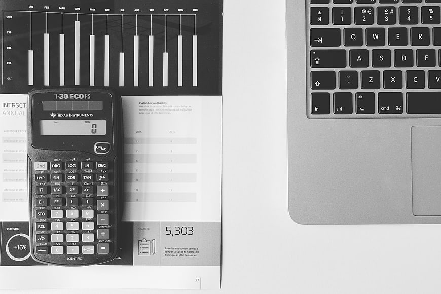Black and white calculator and laptop on financial report
