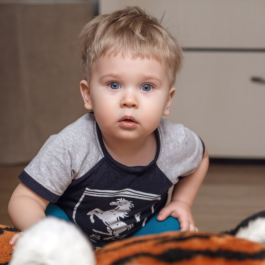 Cute toddler boy with blue eyes crawling on floor