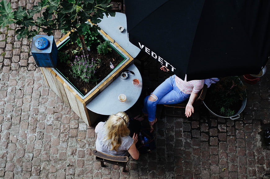 Overhead view of two women relaxing at outdoor cafe table