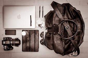 Flat lay of photographer gear with leather bag and laptop