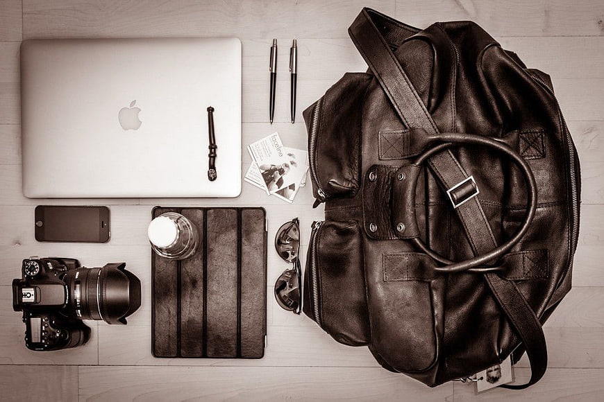 Flat lay of photographer gear with leather bag and laptop