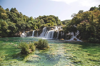 Crystal Clear Turquoise Waterfall with Swimmers in Lush Forest