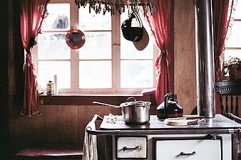 Rustic kitchen interior with wood stove and red curtains