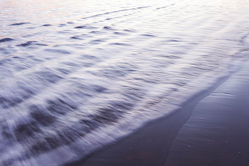 Long Exposure Ocean Waves Washing Over Dark Sandy Beach