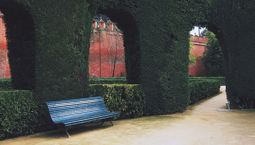 Blue Bench in Garden with Hedge Arches and Red Brick Wall