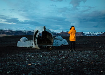 Traveler in Yellow Jacket Photographing Plane Wreck in Iceland