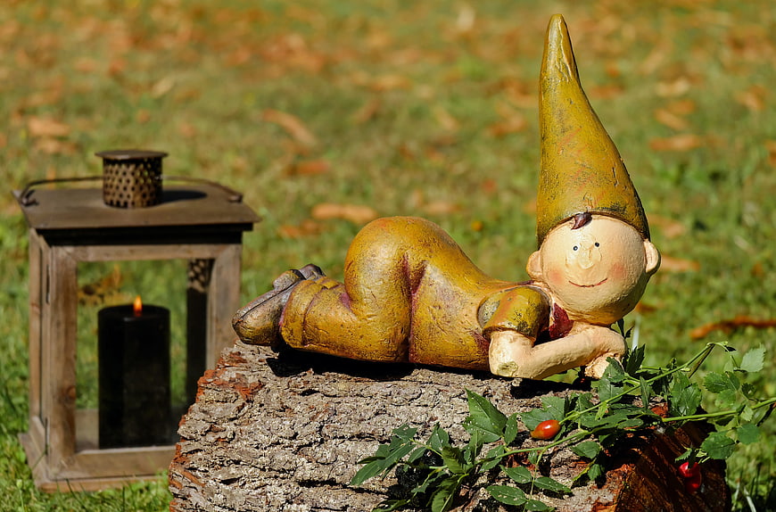 Funny wooden garden gnome lying on tree stump
